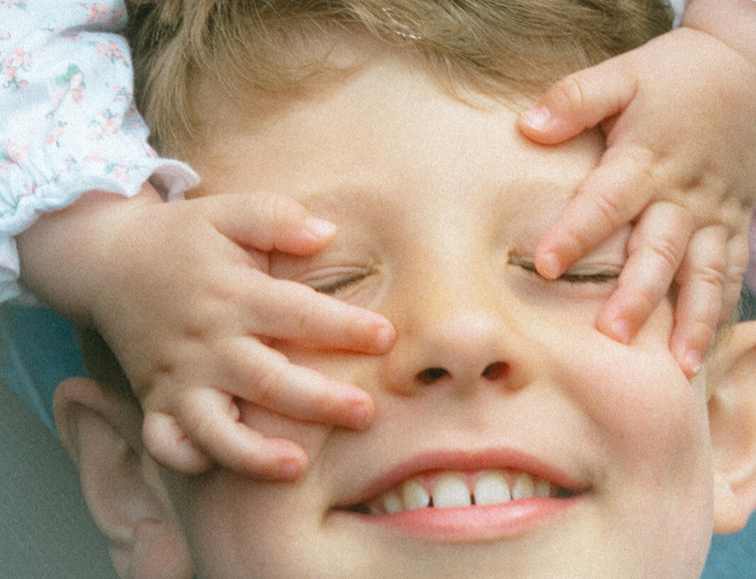 Lincoln Natural Family Photography Zoom in of baby girl's hands on older cousin's face while he smiles. Taken at Bailand Lodge, Woodhall Spa, Lincolnshire